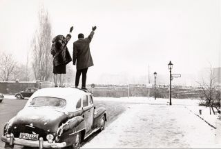 Léon Herschtritt : "Noël à Berlin. A l'angle d'une rue enneigée depuis Bergtrasse, un couple debout sur le toit d'une voiture lève le bras pour saluer de l'autre côté du mur vers Berlin Est" 1961 (c) Paris, Musée de l'Armée/Emilie Cambier/Léon Herschtritt